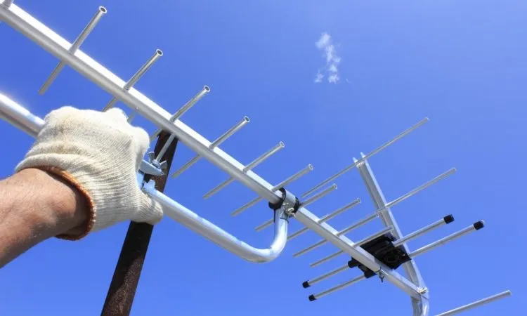 Technicien antenniste réglant une antenne TV